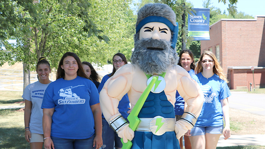 The Skylander mascot stands with several female students