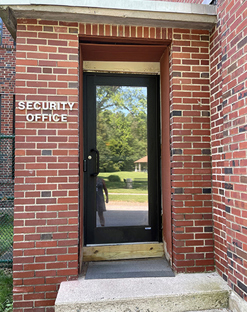 Image of the entrance to the Security Office, full length glass door on a brick building.