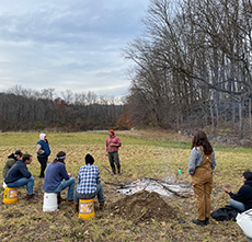 Students sit in the field at the farm planning their crops