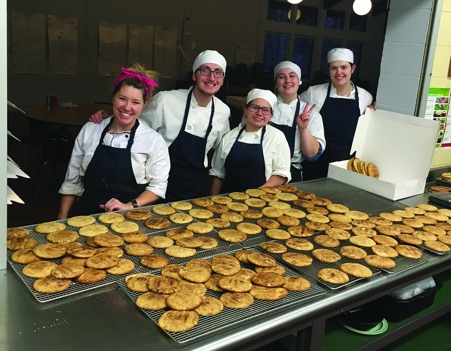 A group of Culinary students stand in front of trays of cookies