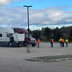 Two Tractor trailers in a parking lot and several people standing around.
