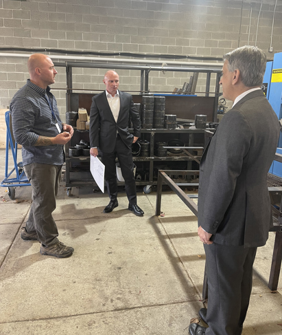 Three men stand in a Welding shop