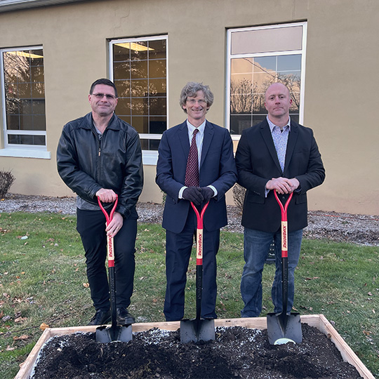 Three business men with shovels at a groundbreaking ceremony.