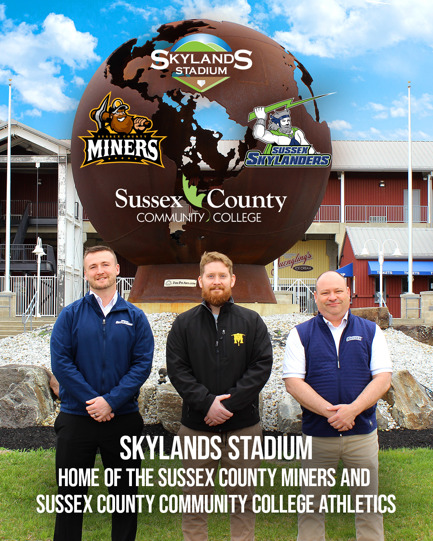 Three men stand in front of a stadium.