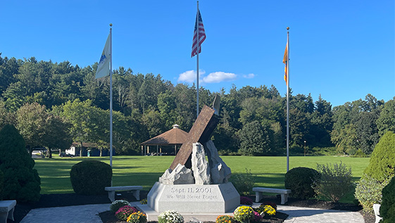 A steel beam memorial with flags and flowers