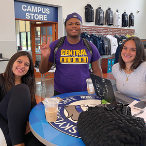 3 students (2 female and 1 male) sitting in the cafe.
