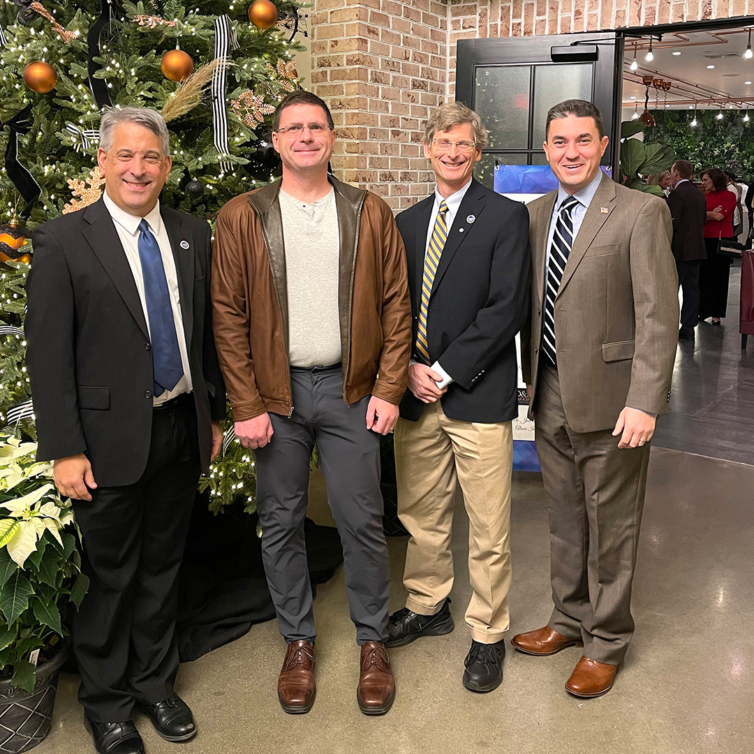 4 men standing in front of a Christmas tree