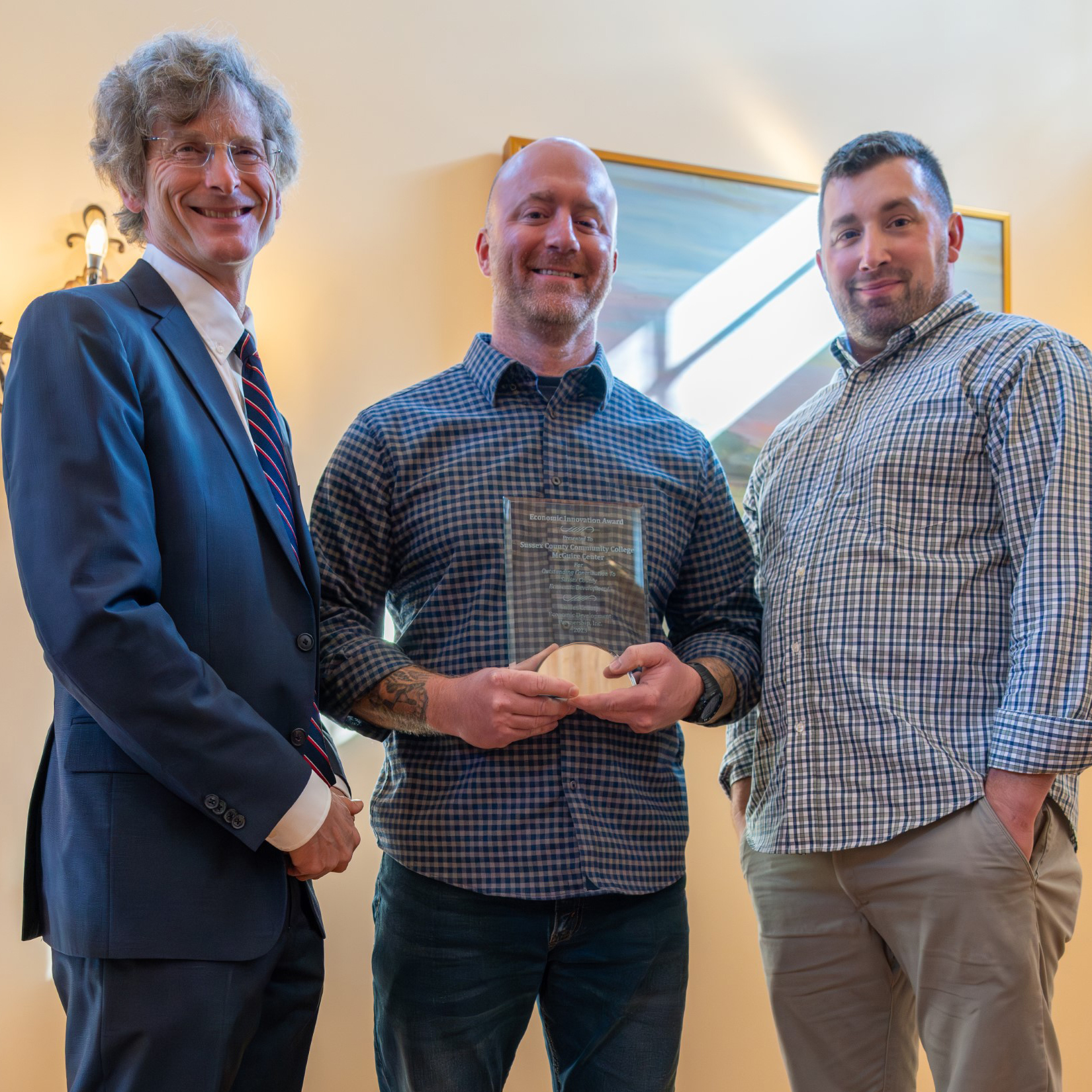 Three men stand holding a crystal trophy.