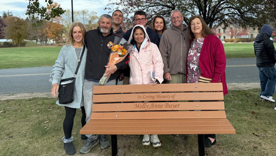 A bench with family members standing in memory.